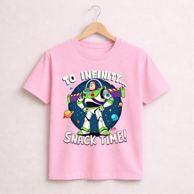 May include: A light pink t-shirt featuring Buzz Lightyear from Toy Story. The graphic shows Buzz in his spacesuit with the text "TO INFINITY... SNACK TIME!" in a blue circle with stars and planets.