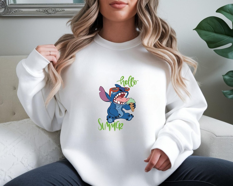 Puede incluir: Sudadera blanca con un personaje de dibujos animados Stitch con gafas de sol y un helado. Las palabras "hello Summer" est&aacute;n escritas en verde. La sudadera es de estilo casual.