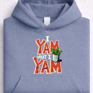 May include: A light blue hoodie with a front pocket and a hood. The front of the hoodie features the text "I Yam What I Yam" in red and white, with a small illustration of a plant in a pot.