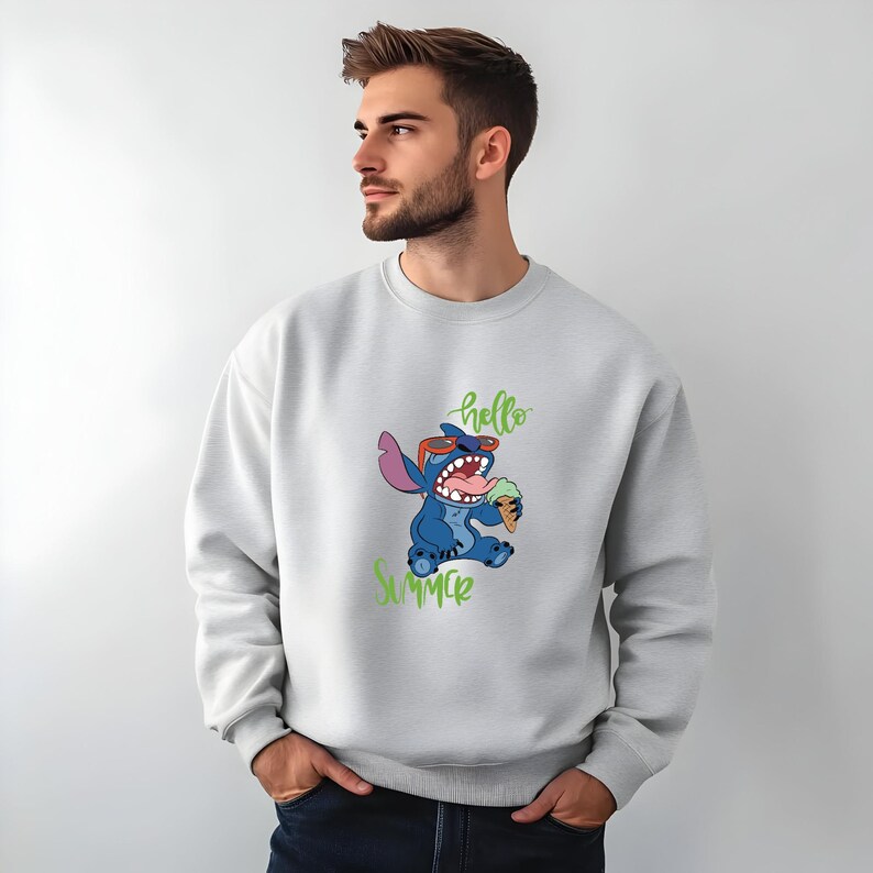 Puede incluir: Sudadera gris claro con un dise&ntilde;o de Stitch sosteniendo un helado. Stitch, un personaje azul, lleva gafas de sol rojas. Las palabras "hello summer" en verde est&aacute;n escritas arriba y abajo.
