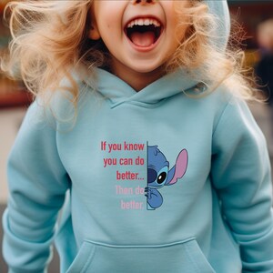 Puede incluir: Sudadera con capucha azul claro con un gr&aacute;fico del personaje Stitch de Lilo & Stitch, con el texto "If you know you can do better... Then do better." La sudadera tiene un bolsillo delantero y una capucha.