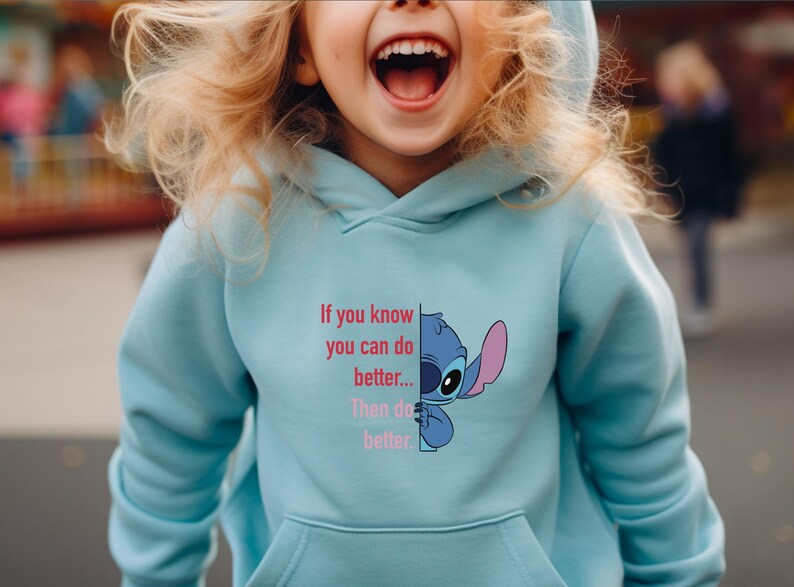 Puede incluir: Sudadera con capucha azul claro con un gr&aacute;fico del personaje Stitch de Lilo & Stitch, con el texto "If you know you can do better... Then do better." La sudadera tiene un bolsillo delantero y una capucha.