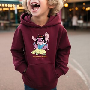 May include: Burgundy hoodie with a cartoon graphic of a character dressed as a princess. The graphic includes the text "You make me feel like a princess". The hoodie has a front pocket and a hood.