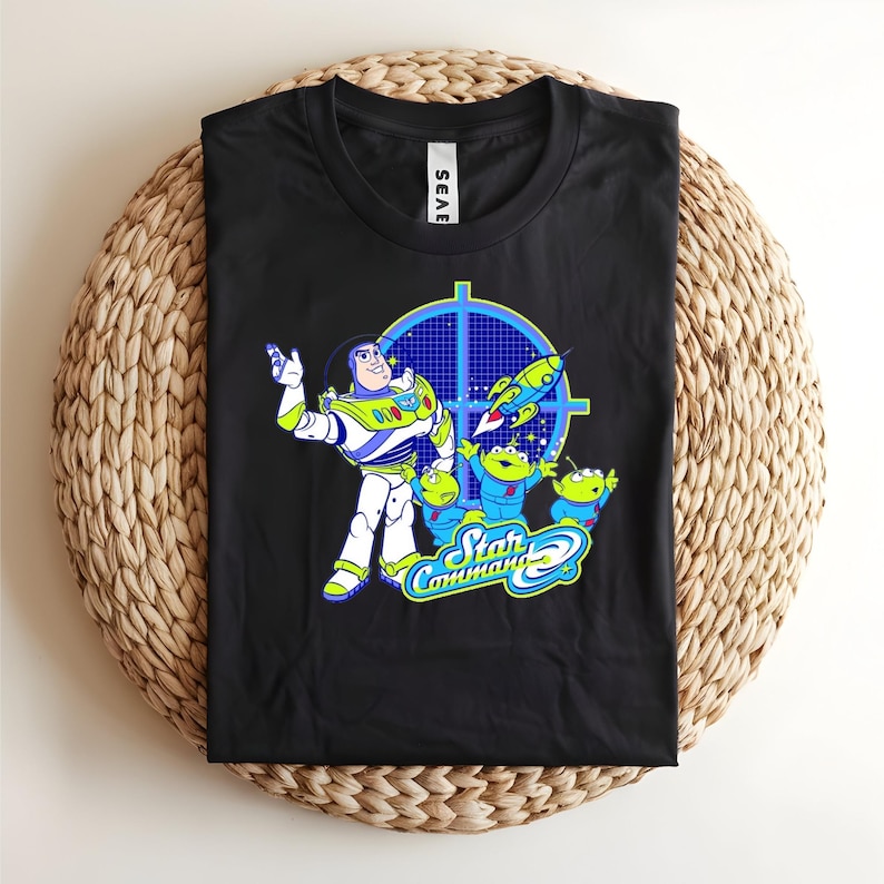 May include: Black t-shirt featuring Buzz Lightyear and the Little Green Men from Toy Story. The design includes the words "Star Command" in a blue and green font, with a blue target graphic and a rocket ship.