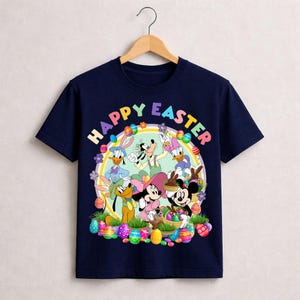May include: Navy blue t-shirt featuring a colorful graphic of Disney characters, including Mickey and Minnie Mouse, Donald Duck, and Goofy, with the text "HAPPY EASTER". The design includes Easter eggs and flowers.