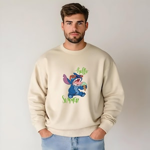 Puede incluir: Sudadera beige con un personaje de dibujos animados con gafas de sol sosteniendo un helado, con las palabras "hello SUMMER" en verde. La sudadera es de color neutro y tiene cuello redondo.