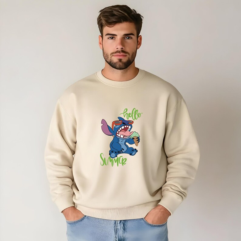 Puede incluir: Sudadera beige con un personaje de dibujos animados con gafas de sol sosteniendo un helado, con las palabras "hello SUMMER" en verde. La sudadera es de color neutro y tiene cuello redondo.