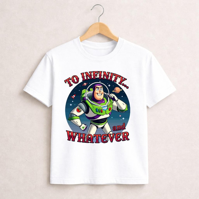 Puede incluir: Camiseta blanca con una ilustraci&oacute;n de dibujos animados de Buzz Lightyear de Toy Story. El dise&ntilde;o muestra a Buzz con su traje espacial, un fondo estrellado y el texto "TO INFINITY... and WHATEVER" en letras rojas y blancas. La camiseta est&aacute; colgada en una percha de madera.