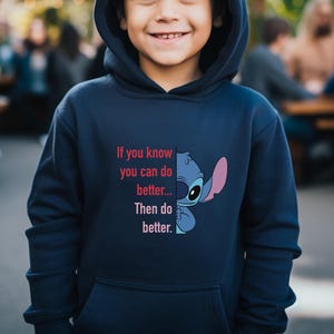Puede incluir: Sudadera con capucha azul marino con un gr&aacute;fico del personaje Stitch de Lilo & Stitch. La sudadera tiene el texto "If you know you can do better... Then do better." en rojo y blanco.
