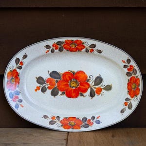 May include: Oval serving platter with a speckled cream background and a floral design. The flowers are bright orange with dark gray and brown leaves and accents. The platter has a dark gray border.