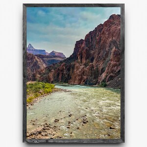 May include: A framed landscape photograph of a river flowing through a canyon. The canyon walls are reddish-brown, and the water is a turquoise color. The sky is a mix of blue and gray.