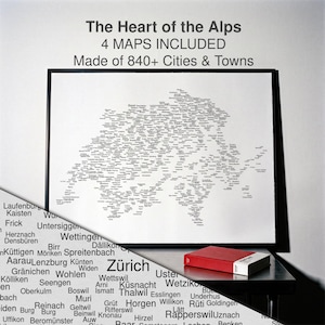 Può includere: Una mappa tipografica incorniciata della Svizzera intitolata The Heart of the Alps, composta da oltre 840 città e paesi. La stampa presenta testo nero su sfondo bianco. Un libro rosso è appoggiato su una superficie nera davanti alla mappa, con un dettaglio ingrandito del testo nell'angolo in basso a sinistra.