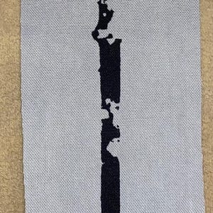 Op de afbeelding: Een zwart zwaardontwerp is gedrukt op een rechthoekige, lichtgrijze stoffen patch. Het zwaard heeft een gedetailleerde pareerstang en een lang, recht lemmet. De patch is rechthoekig en heeft een getextureerd oppervlak.