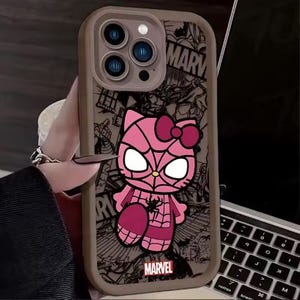 May include: A phone case featuring a pink cartoon character with a spiderweb design, bow, and large eyes. The case has a gray border and a Marvel logo. The background includes comic book-style illustrations and the word "MARVEL".