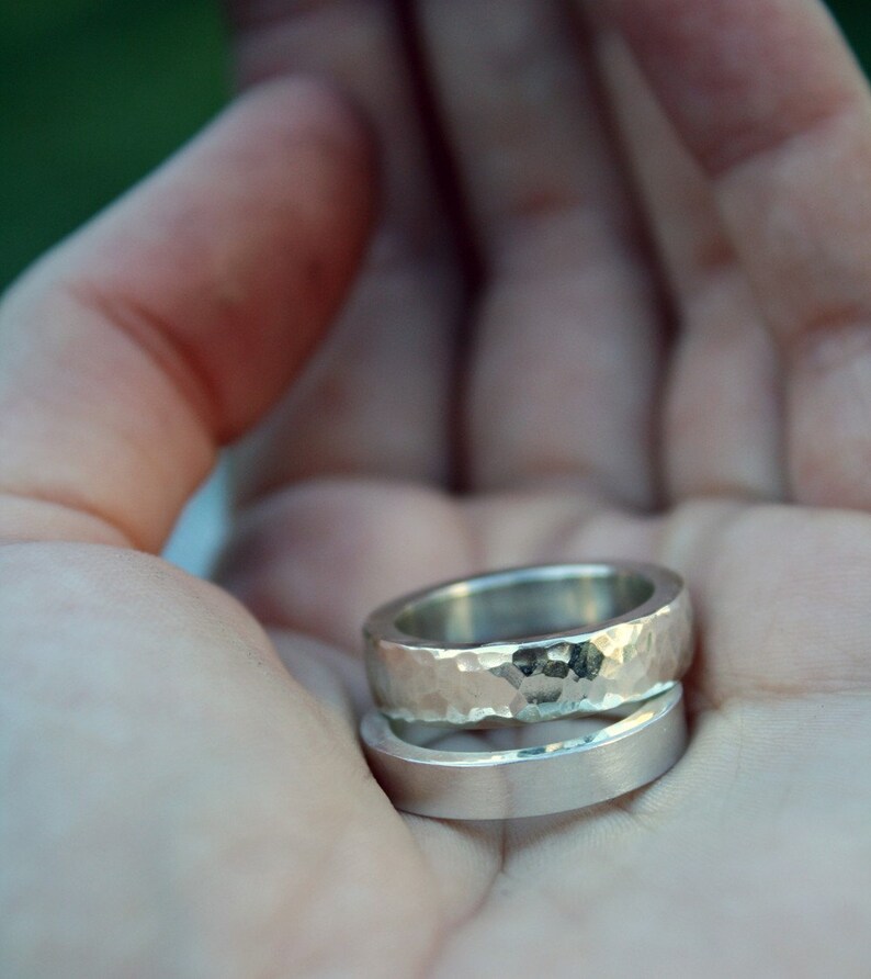 May include: Two silver rings, one with a hammered texture and the other smooth, are stacked on top of each other.