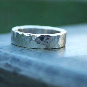 May include: A silver hammered band ring with a textured surface.