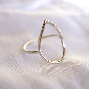 Op de afbeelding: Een zilveren ring met een traanvormige uitsparing. De ring is simpel en elegant.
