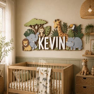May include: A nursery wall decoration featuring the name "KEVIN" in large white letters, surrounded by wooden cutouts of jungle animals, including a lion, elephant, giraffe, and toucan. The decor is set in a light green and beige room with a wooden crib.