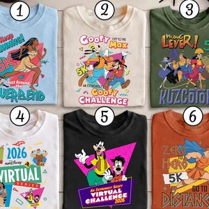 Puede incluir: Seis camisetas gráficas con diseños de personajes de dibujos animados y temas de eventos de carrera. Las camisetas presentan personajes como Pocahontas, Goofy y Hércules. Las camisetas son de varios colores, incluyendo azul, blanco, negro y naranja, con texto como "5K".