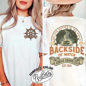 Op de afbeelding: Wit T-shirt met een Jungle Cruise-ontwerp. De voorkant heeft een scheepswielafbeelding met de tekst "Jungle Cruise". De achterkant toont de tekst "The 8th Wonder of the World" en "Backside of Water" met een bootillustratie. "Jungle Cruise Co. EST 1931" is ook gedrukt.