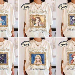 May include: Ivory-colored t-shirts with various framed portraits of animated characters. Each shirt features a different image and text, including "Meet Me At Midnight," "Enchanted To Meet You," and "Look What You Made Me Do."