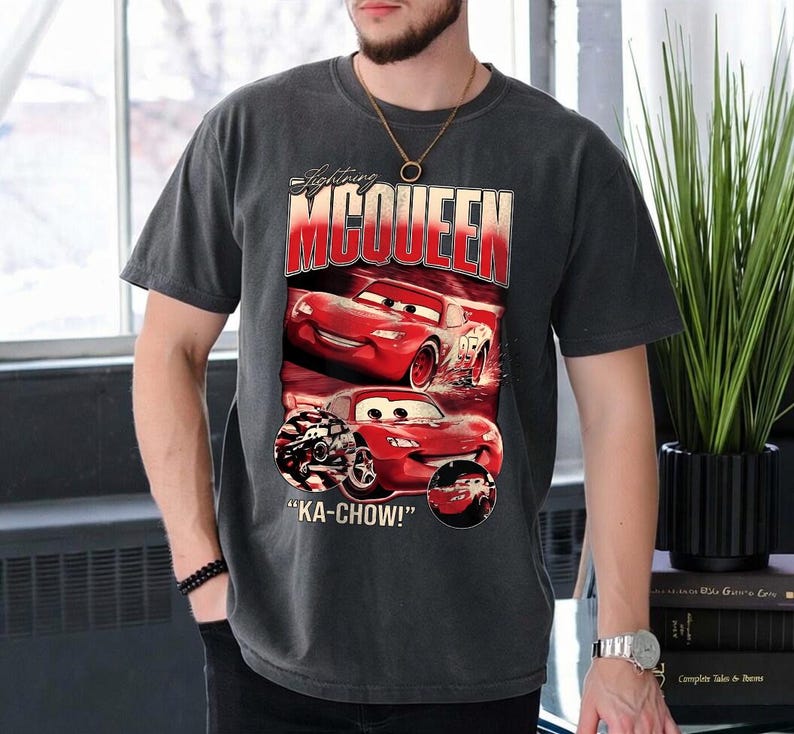 Puede incluir: Camiseta gris oscuro con Lightning McQueen de la pel&iacute;cula Cars. El dise&ntilde;o incluye im&aacute;genes del coche de carreras rojo y el texto "Lightning McQueen" y "KA-CHOW!". La camiseta tiene un aspecto vintage.