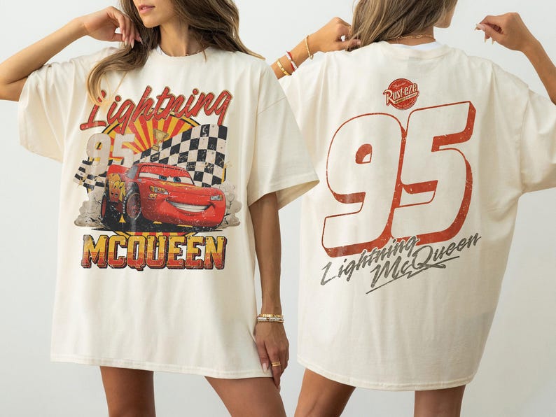 May include: Cream-colored Lightning McQueen t-shirt. The front features a graphic of the red race car, the number 95, and the name McQueen. The back displays a large number 95 and the words "Lightning McQueen".