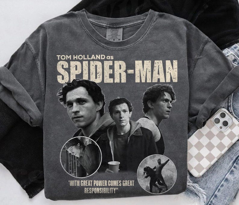 May include: Gray, vintage-style Spider-Man t-shirt featuring Tom Holland. The design includes multiple images of the actor, the words "TOM HOLLAND AS SPIDER-MAN," and the quote "WITH GREAT POWER COMES GREAT RESPONSIBILITY."