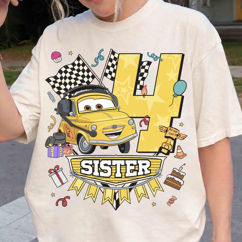 May include: Cream-colored t-shirt featuring a yellow cartoon car with headphones, a checkered flag, and the number 4. The word "SISTER" is displayed on a banner below the car, with birthday-themed graphics.