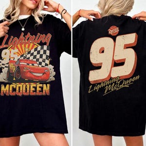 May include: Black t-shirt featuring Lightning McQueen from the Cars movie. The front graphic shows McQueen with the number 95, a checkered flag, and the text "Lightning McQueen". The back of the shirt displays the number 95 and "Lightning McQueen".