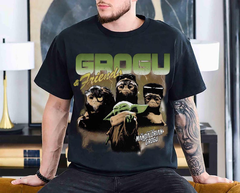 Pu&ograve; includere: T-shirt nero con la scritta "GROGU & Friends" in verde e giallo. La grafica include Grogu e altre tre creature. Sotto c'&egrave; la scritta "THE MANDALORIAN GROGU".