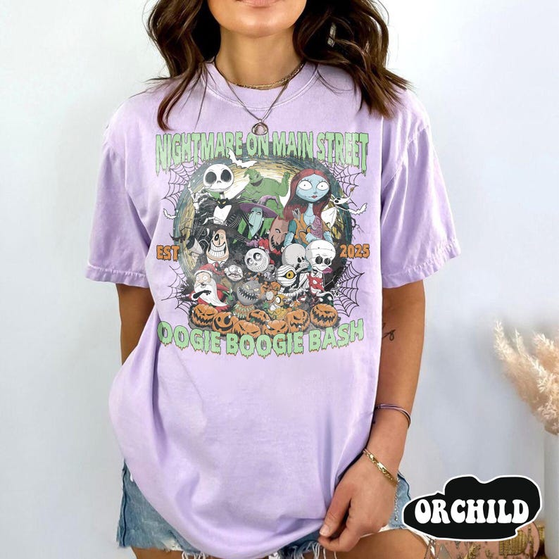 Puede incluir: Una camiseta de color lila claro con un dise&ntilde;o gr&aacute;fico que presenta personajes de una pel&iacute;cula. El dise&ntilde;o incluye el texto "NIGHTMARE ON MAIN STREET" y "DOOGIE BOOGIE BASH" con el a&ntilde;o "2025". La camiseta tiene mangas cortas.