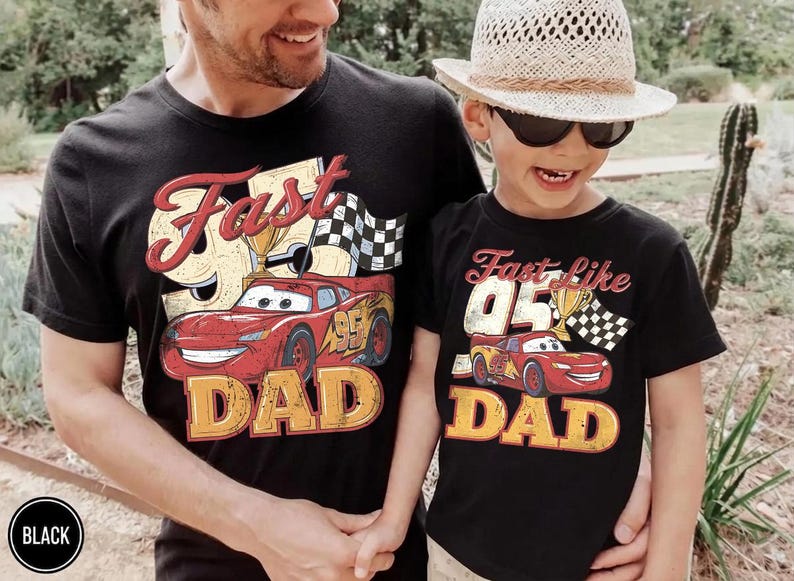 May include: Black t-shirts with matching designs. One shirt says "Fast 95 DAD" with a red race car graphic, a trophy, and a checkered flag. The other says "Fast like 05 DAD" with a similar design.