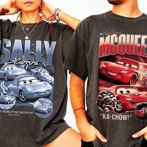 Puede incluir: Dos camisetas gris carb&oacute;n con gr&aacute;ficos de la pel&iacute;cula Cars. Una camiseta muestra "SALLY Carrera" con im&aacute;genes de un coche azul claro. La otra camiseta muestra "Lightning McQueen" con ilustraciones de coches rojos y la frase "KA-CHOW!"