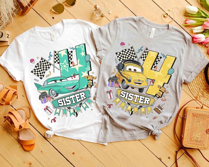 May include: Two t-shirts, one white and one gray, featuring a cartoon car design. The shirts have the number "4" and the word "SISTER" on them. The white shirt has a teal car, and the gray shirt has a yellow car.