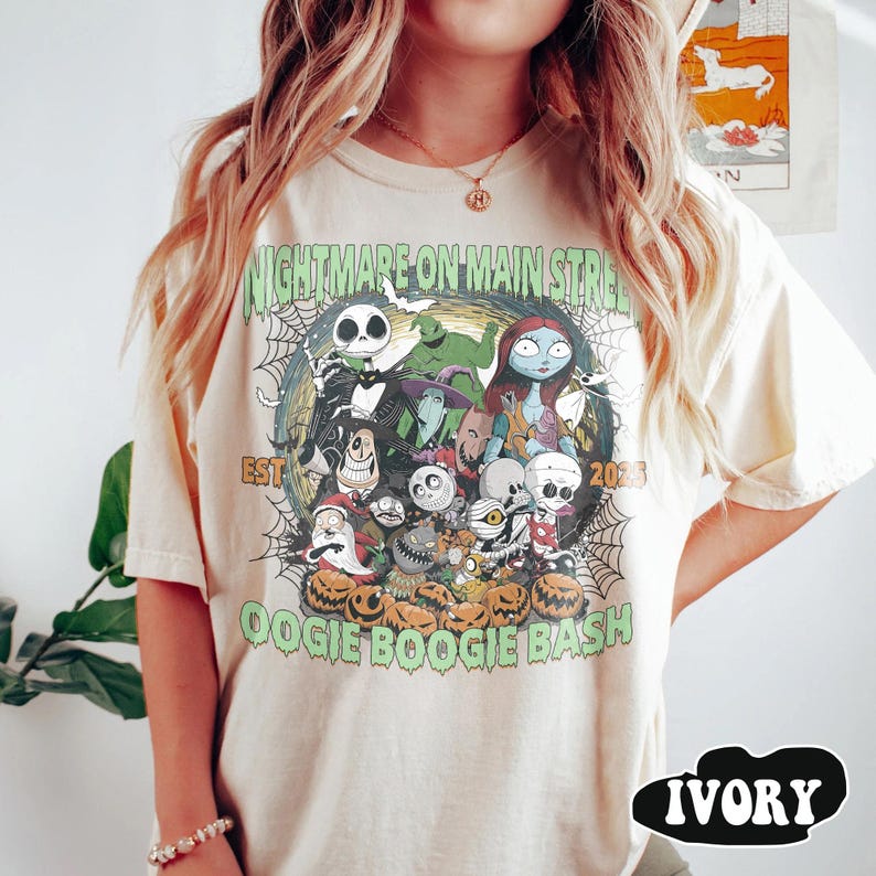Puede incluir: Camiseta color marfil con un dise&ntilde;o gr&aacute;fico de "Pesadilla antes de Navidad". El dise&ntilde;o incluye a Jack Skellington, Sally y otros personajes, con texto que dice "Nightmare on Main Street" y "Oogie Boogie Bash".