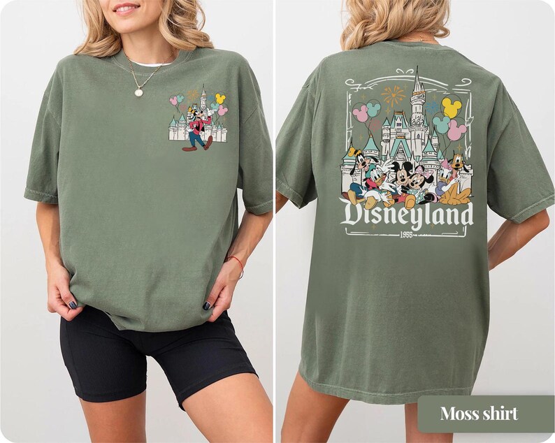 Pode incluir: Camiseta verde musgo com um gr&aacute;fico da Disneyland na frente e atr&aacute;s. O gr&aacute;fico frontal mostra Pateta com bal&otilde;es e um castelo. O gr&aacute;fico traseiro exibe Mickey Mouse, Minnie Mouse, Pato Donald e outros personagens com o logotipo da Disneyland.