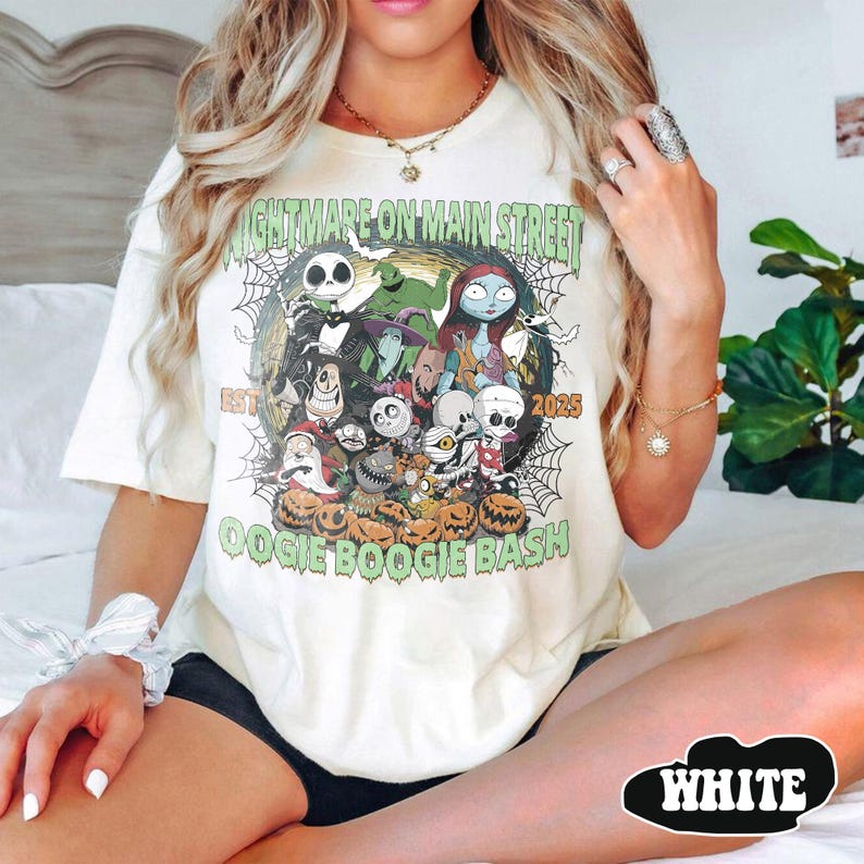 Puede incluir: Camiseta color crema con un dise&ntilde;o gr&aacute;fico con personajes de "Pesadilla antes de Navidad". El dise&ntilde;o incluye a Jack Skellington, Sally y otros personajes, con el texto "Nightmare on Main Street" y "Oogie Boogie Bash."