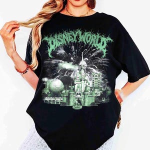 K&ouml;nnte beinhalten: Schwarzes T-Shirt mit einem gr&uuml;nen Aufdruck des Disney World-Logos und einem Schloss mit Feuerwerk. Die Grafik enth&auml;lt auch das Spaceship Earth und andere Geb&auml;ude. Das T-Shirt hat einen Rundhalsausschnitt und kurze &Auml;rmel.