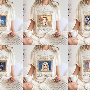 May include: Cream-colored t-shirts with various Disney princess-themed designs. Each shirt features a framed image of a princess with text such as "Meet Me At Midnight" and "I Love Him". The shirts are worn by a person.
