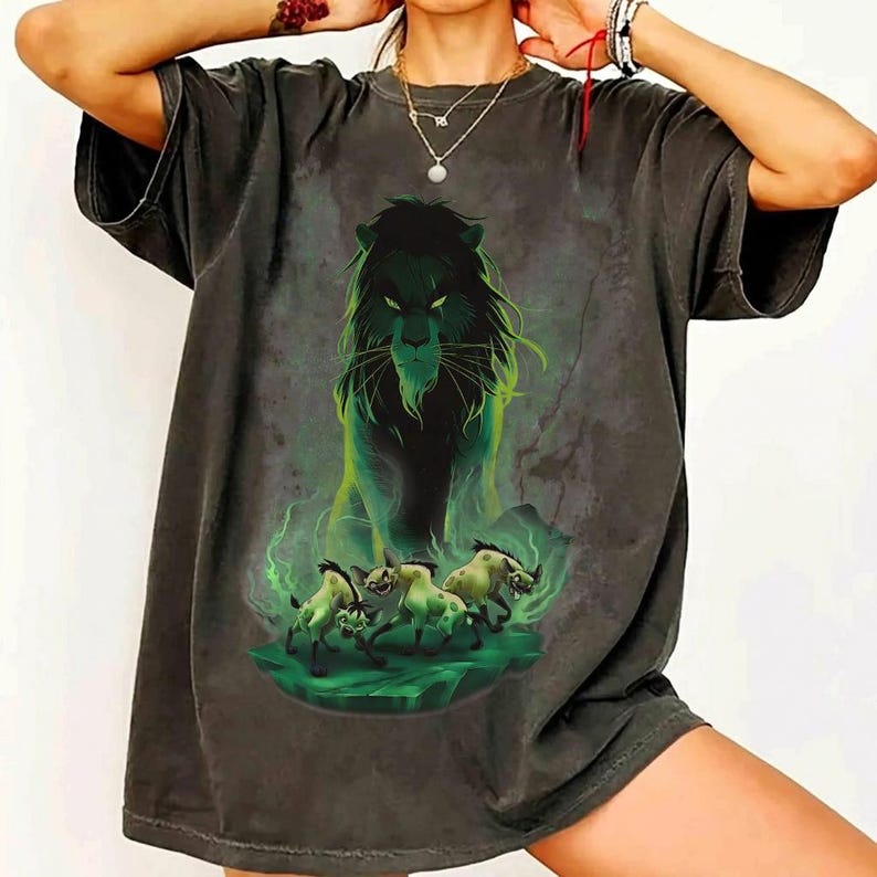 Puede incluir: Camiseta gris oscuro con un dise&ntilde;o de le&oacute;n verde y negro con una expresi&oacute;n amenazante. El dise&ntilde;o incluye detalles verdes e im&aacute;genes de animales corriendo, creando una ilustraci&oacute;n detallada.