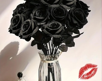 May include: A bouquet of artificial black roses with layered petals and green stems arranged in a clear, vertically ribbed glass vase. A red lip print graphic and the text 5/10pcs are visible in the lower right corner of the image.