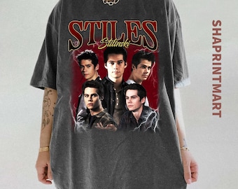 Può includere: T-shirt grigio scuro con una grafica di cinque uomini e la scritta "STILES" in rosso. La maglietta ha un aspetto vintage e usurato. Il testo "SHAPRINTMART" è stampato verticalmente sul lato destro.