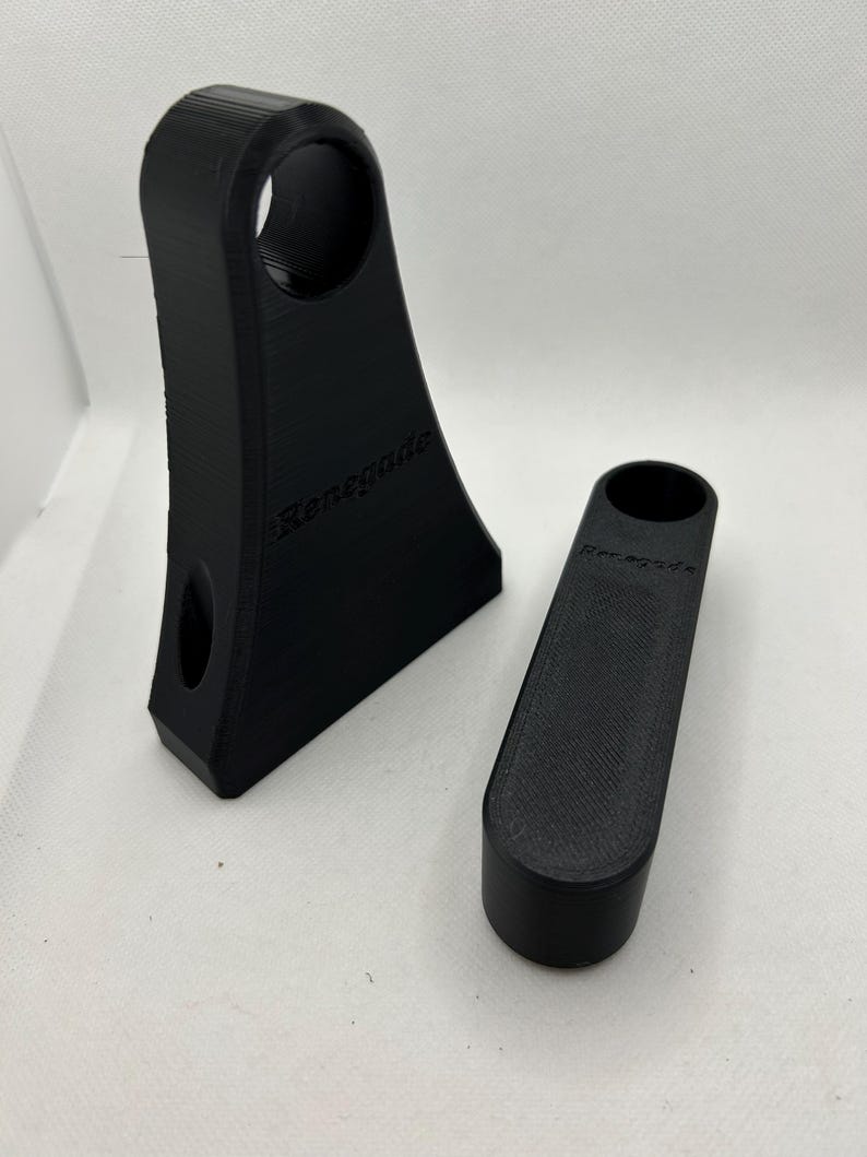 May include: Two black 3D-printed objects. One is a tall, angled piece with a circular hole and the word "Renegade" printed on it. The other is a smaller, cylindrical piece, also with "Renegade" printed on it.