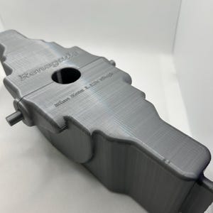 Könnte beinhalten: Ein graues, 3D-gedrucktes Objekt mit den Worten "Renegade" und "Mini Roto L25 Shell" auf der Oberfläche. Das Objekt hat eine einzigartige, asymmetrische Form mit einem zentralen Loch und hervorstehenden zylindrischen Elementen. Der Artikel ist für einen bestimmten Zweck bestimmt.