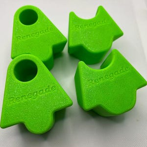 May include: Four bright green, plastic objects with the word "Renegade" embossed on each. The objects have a unique shape, with a rounded top and a hole. The objects are arranged on a white surface.