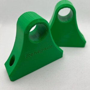 May include: Two bright green, 3D-printed brackets with a curved top and a circular hole. The word "Renegade" is embossed on the side of one bracket. The brackets have a flat base and a smaller hole near the bottom.