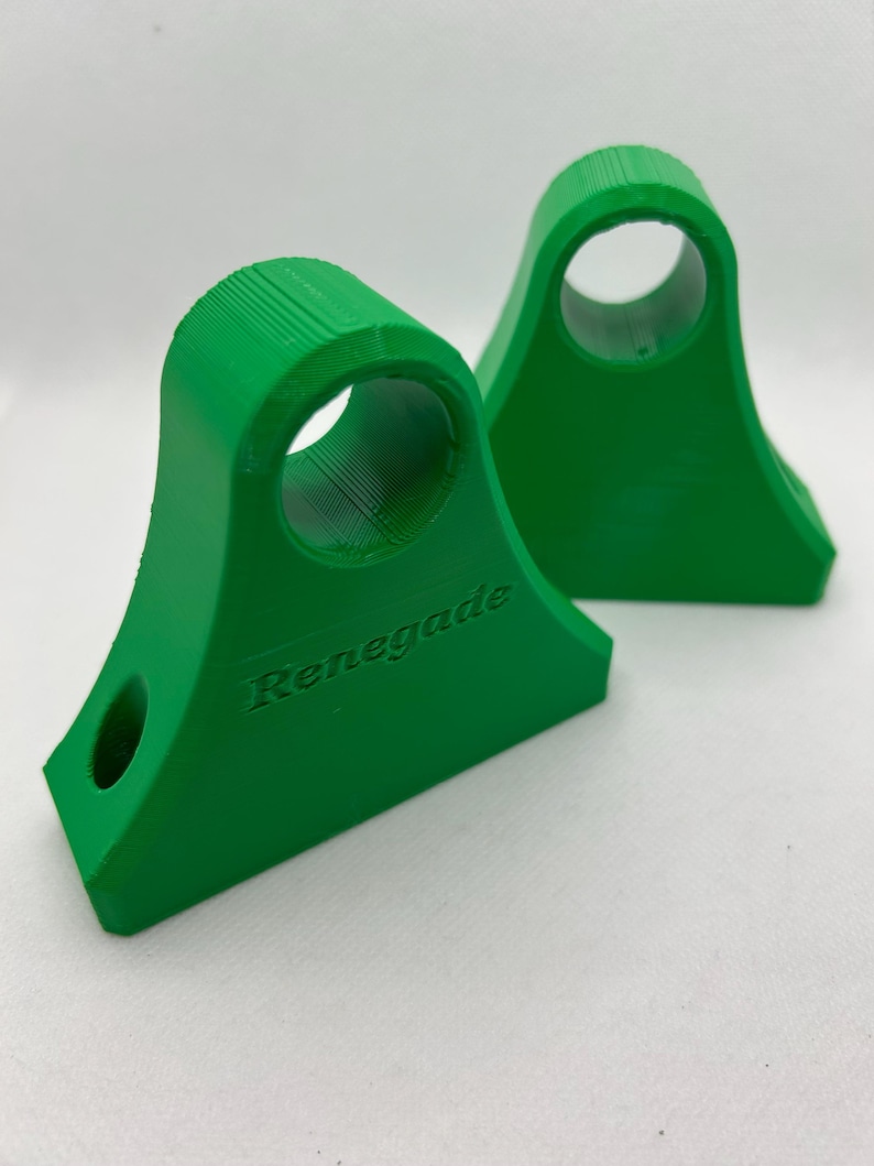 May include: Two bright green, 3D-printed brackets with a curved top and a circular hole. The word "Renegade" is embossed on the side of one bracket. The brackets have a flat base and a smaller hole near the bottom.