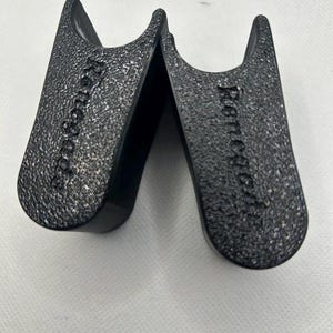 May include: Two black boot shapers with a textured surface. The text "Remodel" is embossed on each shaper. The shapers are designed to maintain the shape of boots when stored.
