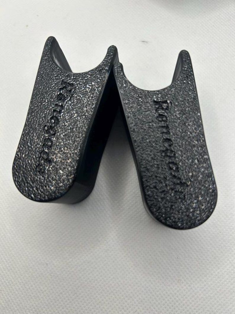 May include: Two black boot shapers with a textured surface. The text "Remodel" is embossed on each shaper. The shapers are designed to maintain the shape of boots when stored.